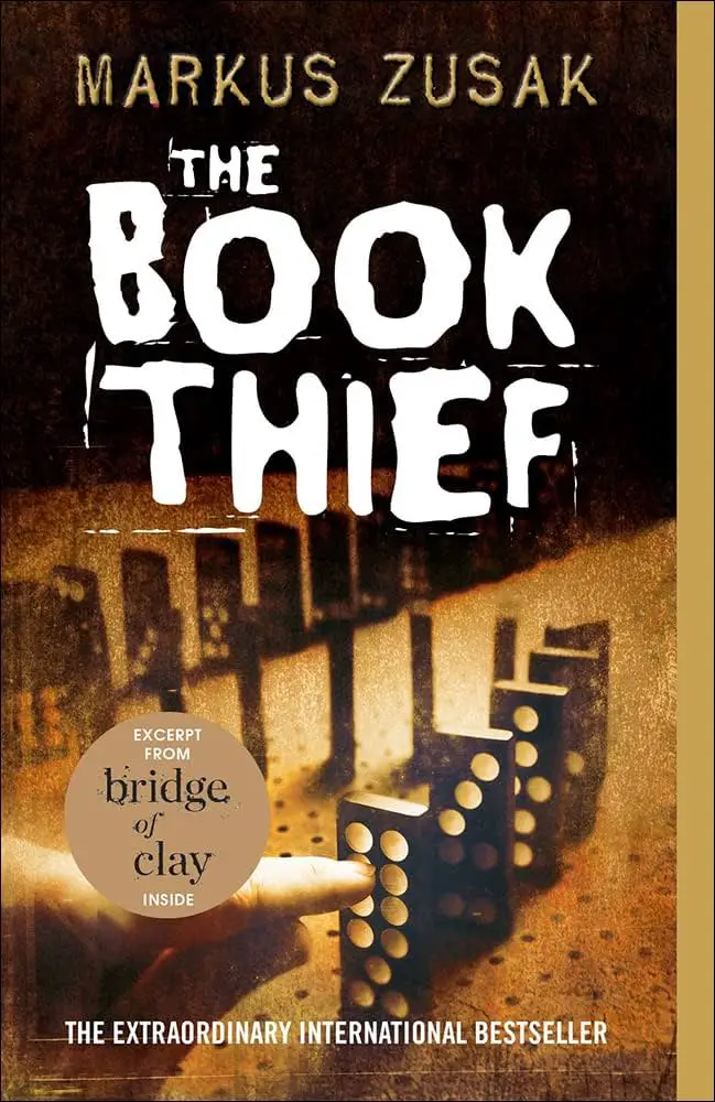 A book cover of The Book Thief by Markus Zusak, featuring a hand toppling a series of dominoes against a dark, textured background