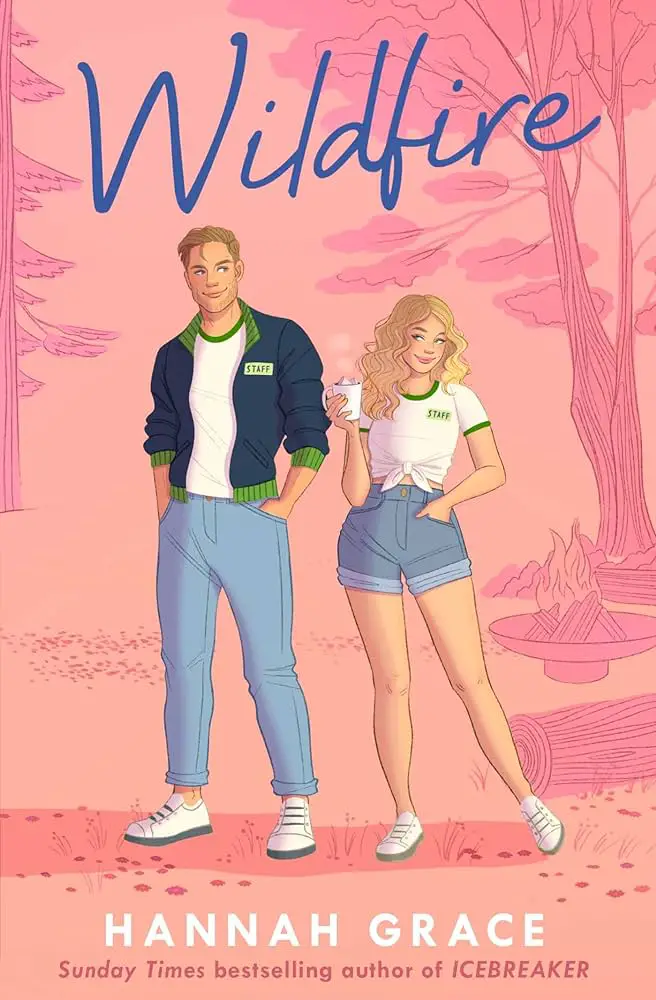 A pastel pink book cover with the title "Wildfire" in large blue cursive font. Below are two illustrated characters: a young man in a blue jacket and jeans, and a young woman in a white crop top and denim shorts, holding a drink. Both have "STAFF" on their shirts. At the bottom, "Hannah Grace" is written in white capital letters, with "Sunday Times bestselling author of ICEBREAKER" below it.