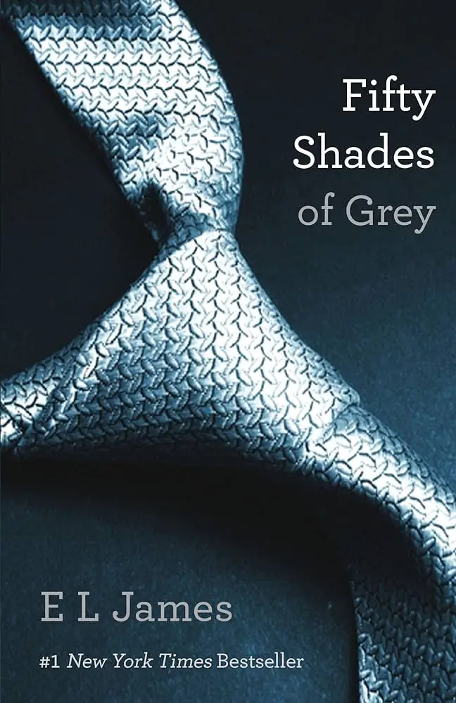 "Book cover of 'Fifty Shades of Grey' by E. L. James. The image features a close-up of a silver-grey, textured necktie set against a dark background. The tie is neatly knotted, emphasizing its intricate pattern and sleek appearance. The title and author's name are displayed on the right side of the cover."
