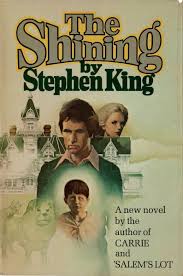 Cover of Stephen King's novel The Shining featuring a man, woman, and boy in the foreground with the eerie Overlook Hotel in the background.