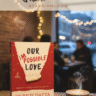 Durjoy Datta's novel Our Impossible Love displayed on a cozy café table with a steaming cup of coffee, eyeglasses, and blurred background of people, promoting free PDF download and online reading at Gyannidhi.com